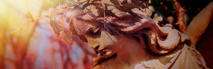 Angel statue in  ivy and sunlight as a symbol of strength, truth and faith.