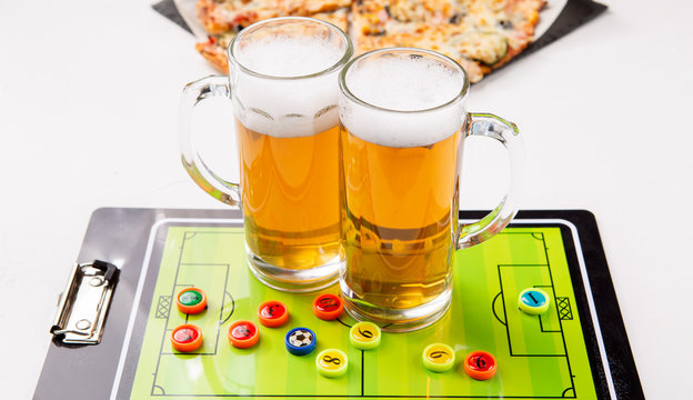 Photo of two mugs of frothy beer, table football