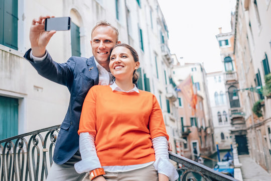 Happy in love couple take selfie photo on one of numerous bridges in Venice