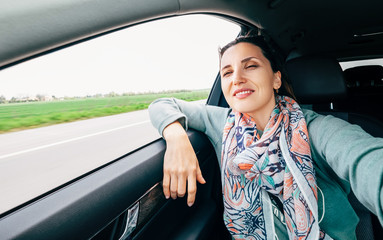 Woman in car portrait with wavy hair looks out car window wide angle shot.