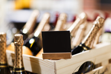 Bottles of champagne in wooden boxes with blank black sign .