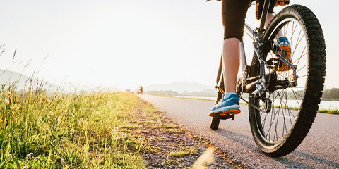 Woman feet on bycikle pedal in sunset light - Powered by Adobe