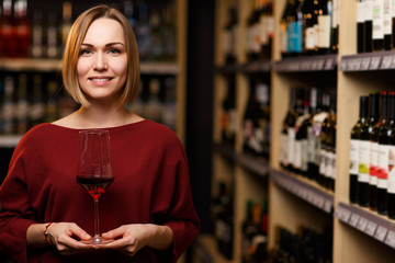 Picture of woman with glass in hands at store with wine