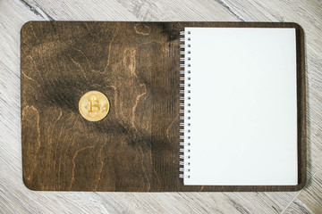 Bitcoin coin on wooden notepad. cost planning cryptocurrency.