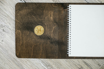 Bitcoin coin on wooden notepad. cost planning cryptocurrency.