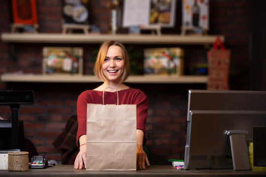 Photo of happy blonde seller with paper bag