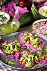 taco keto diet food is wrapped instead of cakes in cabbage leaf of Peking cabbage with avocado mayo, diced avocado, ground beef, onions, corn and cilantro, healthy fats without carbohydrates.