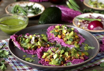 taco keto diet food is wrapped instead of cakes in cabbage leaf of Peking cabbage with avocado mayo, diced avocado, ground beef, onions, corn and cilantro, healthy fats without carbohydrates.