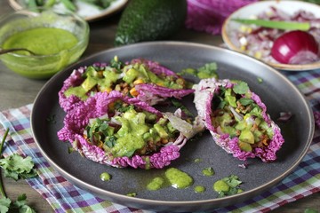 taco keto diet food is wrapped instead of cakes in cabbage leaf of Peking cabbage with avocado mayo, diced avocado, ground beef, onions, corn and cilantro, healthy fats without carbohydrates.