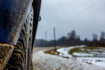 Empty Countryside Landscape in Cloudy Winter Day with Snow Partly Covering the Ground and Fog - Part of the Car in the Foreground