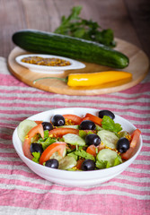 Vegetarian salad of tomatoes, cucumbers, parsley, olives and mustard on linen tablecloth.