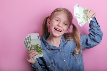 business and money concept - happy little girl with euro cash money over pink background