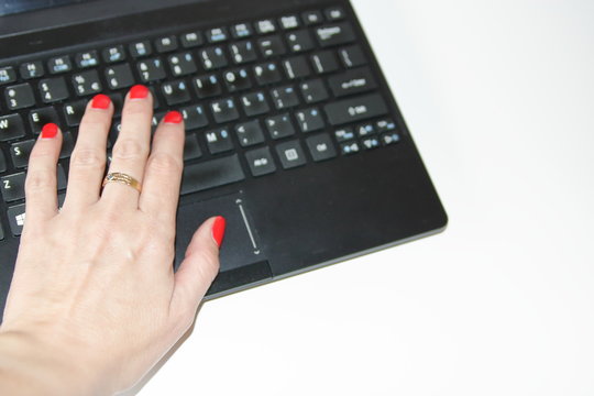 female hand with red painted nails on computer keyboard