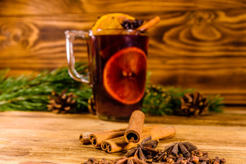 Cup of mulled wine with cinnamon and fir tree branches on wooden table