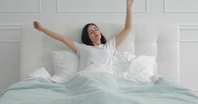 Young girl stretching in bed early morning after waking up