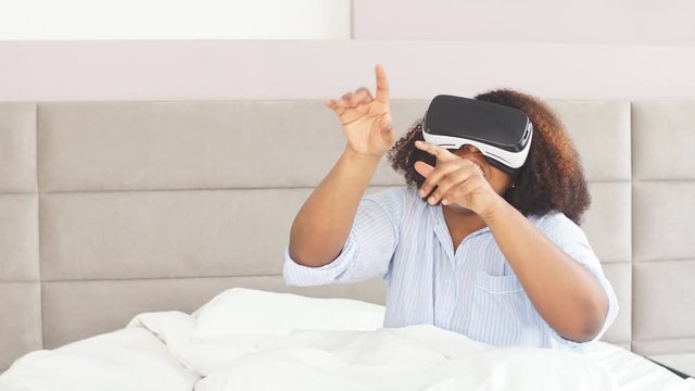 Funny girl pointing at somewhere while using 3D device, entertainment, attractive woman having fun with VR glasses
