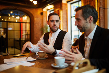 Portrait of two successful business people working in cafe during coffee break, copy space