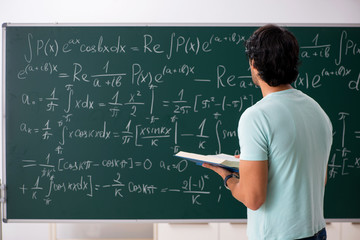 Young male student mathematician in front of chalkboard 