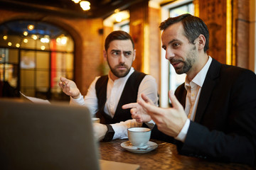 Portrait of two successful business people working in cafe and using laptop, copy space