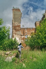 kobieta idzie ceglanych pośród ruin starej fabryki, wysokie ceglane wieże pozostałe po fabryce © Jarek Witkowski