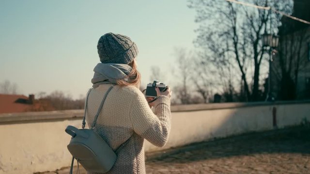 Medium Tracking and Rotating Shot of Young Tourist Woman Walking near Medieval Castle and Taking Pictures by Vintage Camera with Beautiful Sun Glare