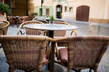 Empty rattan chairs and tables outside a street restaurant at the city
