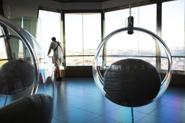 Man looking to the city from the observation deck, near the hanging glass chair