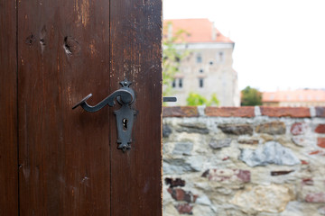 Vintage scratched door knob of a brown wooden door against a city panorama