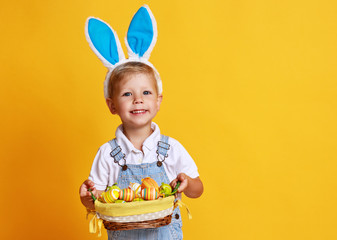 funny happy child boy with easter eggs and bunny ears on yellow