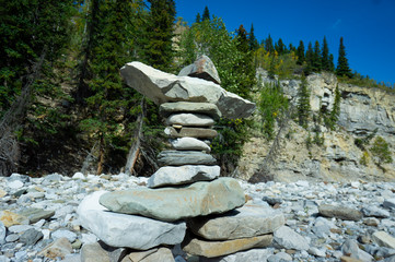 Inuksuk along the rocky shore of a river in the Rocky Mountains of Canada