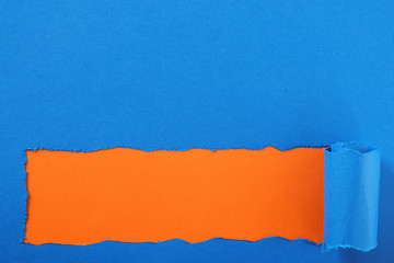 Torn blue paper strip orange background