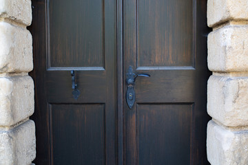 Closeup photo of forged handles on a black wooden door