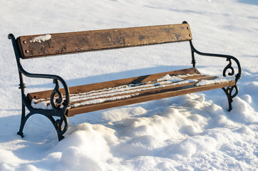 Old rusty vintage empty bench in snow covered park