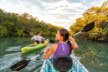 Couple kayaking together in mangrove river of the Keys, Florida, USA. Tourists kayakers touring the...