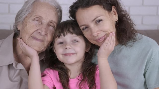 Child holds mother and the old woman. Women of the same family. Granny, mom, daughter.