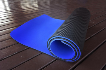 Yoga mat on a wooden background