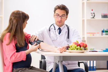 Fototapeta premium Pregnant woman visiting doctor discussing healthy diet