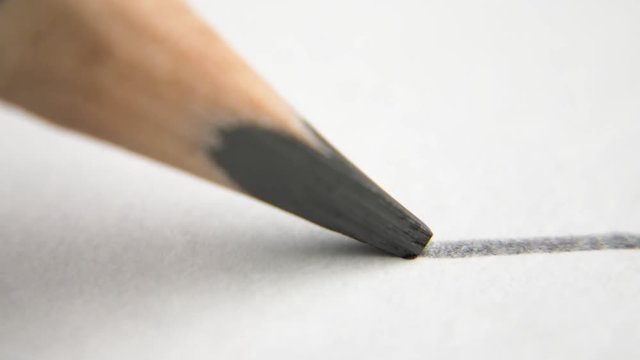extreme close up of architect or artist draws a line in pencil. schoolboy drawing a flat line with a black pencil. Artists hands drawing wooden pencil writes line on paper. tracking shot