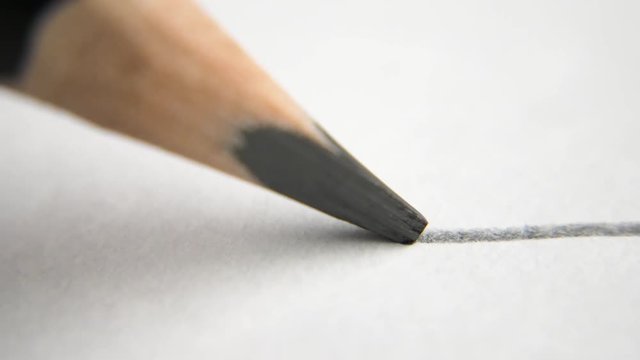 extreme close up of architect or artist draws a line in pencil. schoolboy drawing a flat line with a black pencil. Artists hands drawing wooden pencil writes line on paper. tracking shot