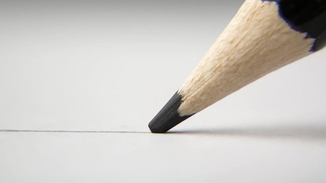 extreme close up of architect or artist draws a line in pencil. schoolboy drawing a flat line with a black pencil. Artists hands drawing wooden pencil writes line on paper. tracking shot