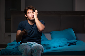 Fototapeta premium Man watching tv at night in bed