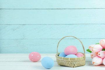 Shot of decoration Happy Easter holiday background concept.Arrangement bunny eggs in wood basket and tulip on the  rustic white & blue wooden table at home office desk.Negative space for creative.