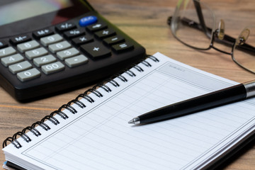 calculator and notebook. glasses in background