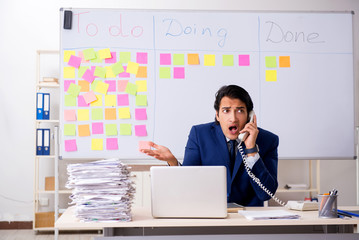 Young handsome employee in front of whiteboard with to-do list  