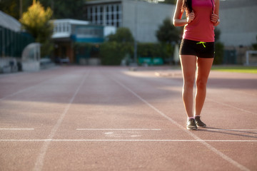 Fototapeta premium one young woman, unrecognizable person, wearing fitness clothes, walking on a sports court. On a track and field, running tracks.