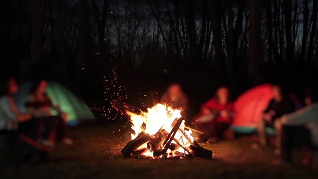 Blurred People Sitting around a Campfire, Blurred Campers and Campfire at Night.