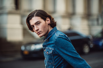 Fototapeta premium Handsome young adult man on city street wearing casual denim jeans shirt