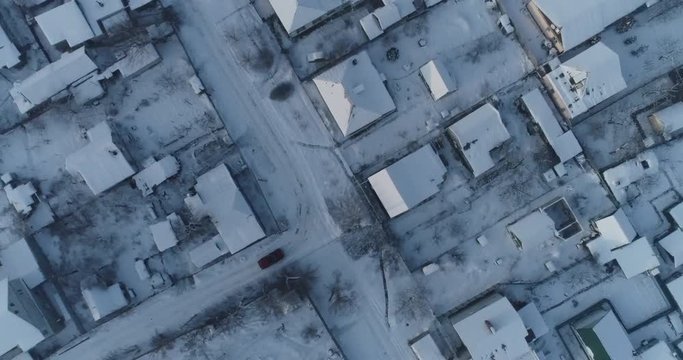 (original 4k file)  SUV shot from a drone moves among the snow-covered roofs of private houses