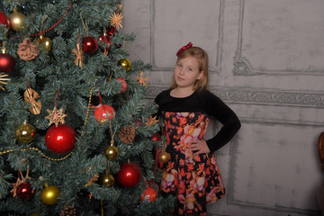 girl blonde child in black with red dress in christmas by the christmas tree