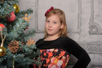 girl blonde child in black with red dress in christmas by the christmas tree